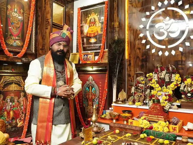 Guruji in the consultation room, with the pooja altar and a birth chart on the table